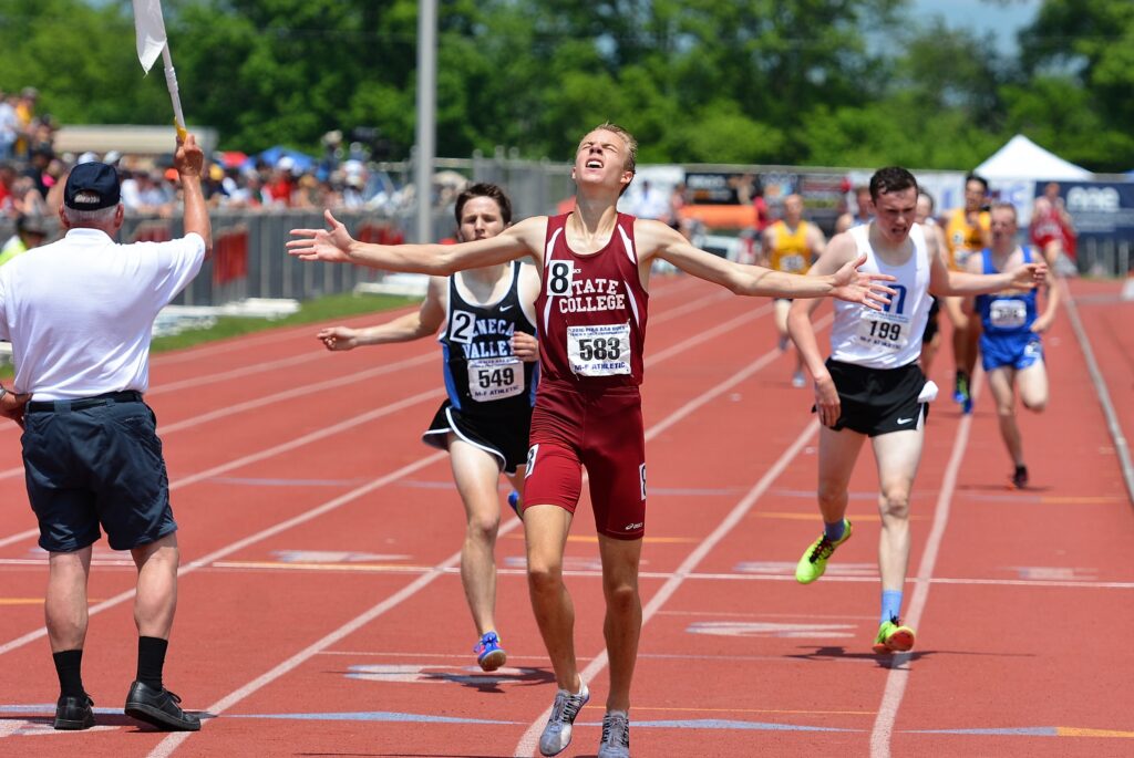 A boy crosses the finish line in a track meet