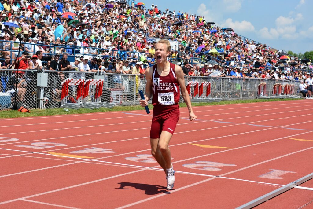 A boy crosses the finish line in a track meet