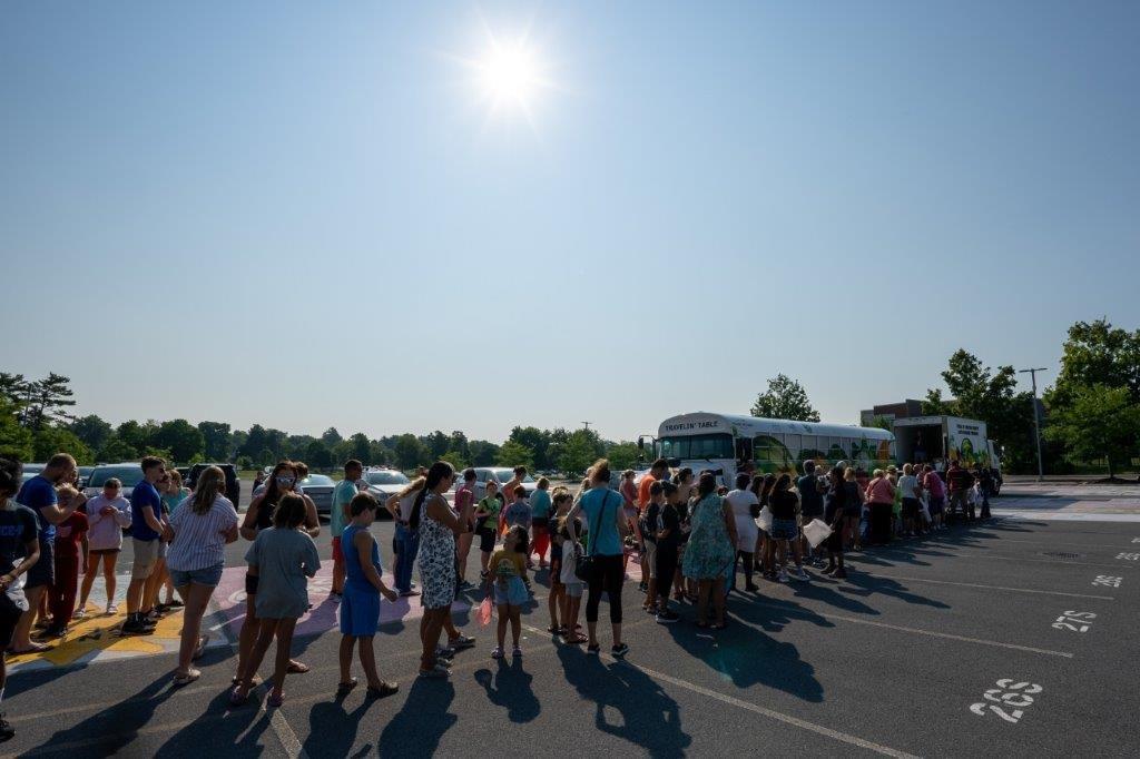 people stand in line at a free farmers market