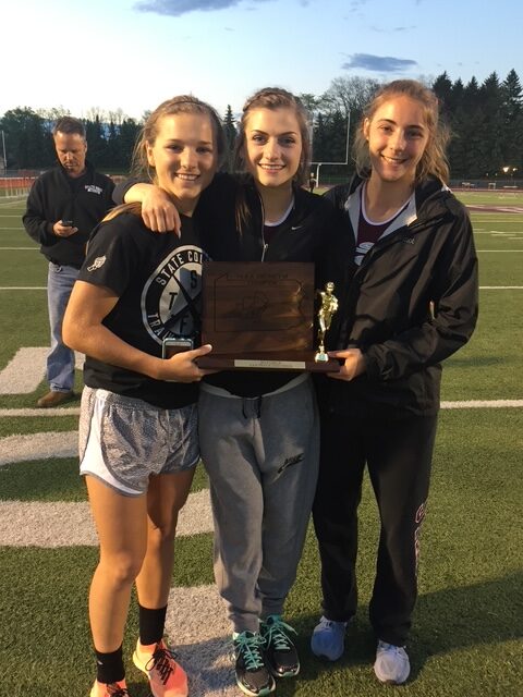 Three girls stand with a trophy.