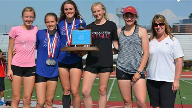 Six female athletes stand with an award.