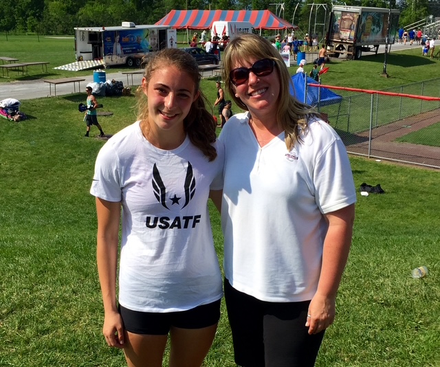 A teenage girl and a woman stand together at a track meet.
