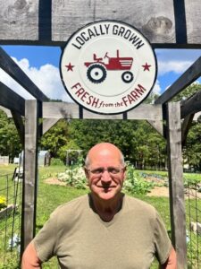 A man stands in front of a farm sand sign