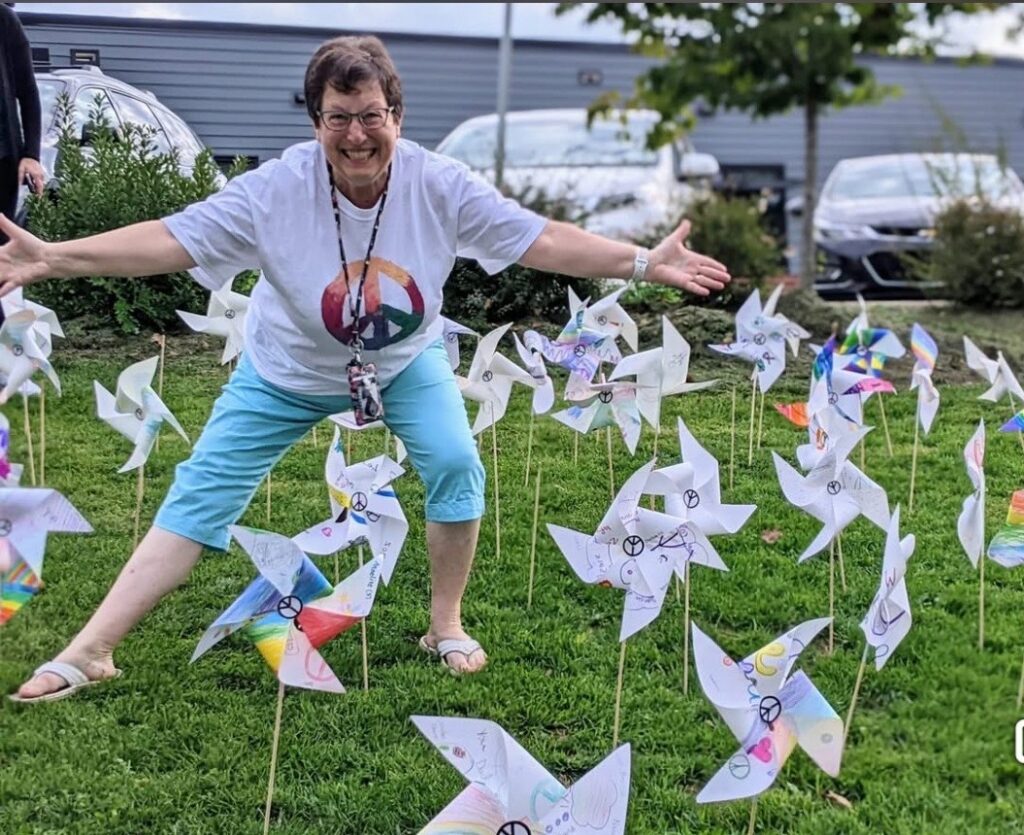 A woman poses in a lawn filled with small windmills