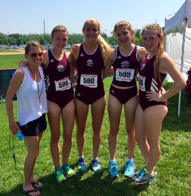 Four girls track team members stand with their coach.